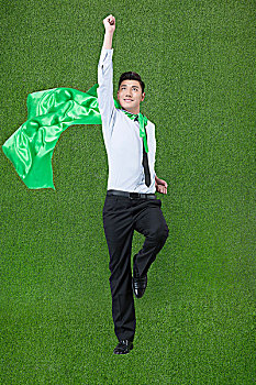 草地商务男士披着绿色披风跳跃