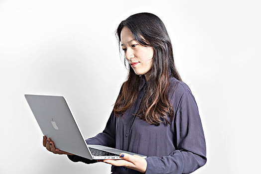 一位站在白色北京前端着电脑的女性