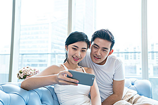 年轻情侣在沙发上使用手机