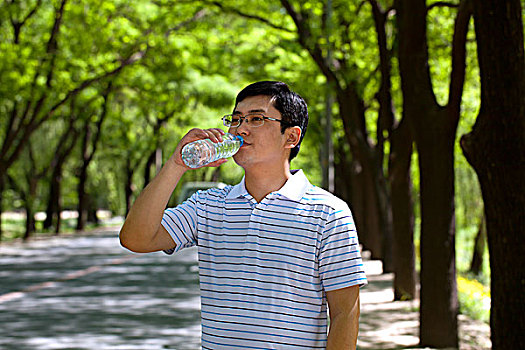 正打开矿泉水瓶子喝水的成功商务男士