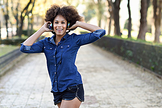 年轻,黑人女性,非洲发型,听,音乐,耳机,城市,背景,混合,有趣,女人,穿,蓝衬衫,短裤