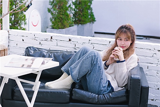 温暖的冬天女生坐在沙发上看书喝咖啡