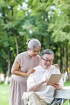 幸福的老年夫妇在户外使用平板电脑上网