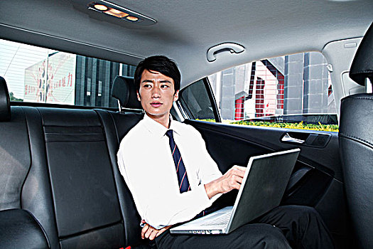 商务男青年坐在车里使用电脑