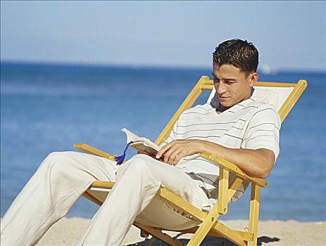 英俊,男青年,坐,休闲椅,读,书本,海滩,海岸线