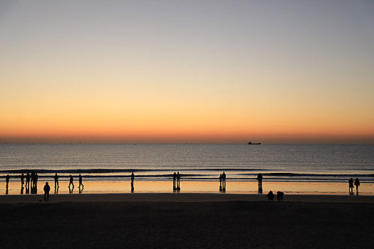 海边绚丽霞光染红天际线,游客惊叹忙打卡拍照
