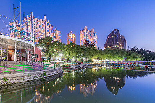 中国北京朝阳公园湖边的树林建筑夜景