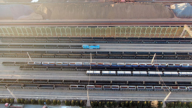 山东省日照市,航拍晨曦里的铁矿石堆场,火车往来穿梭一片繁忙景象
