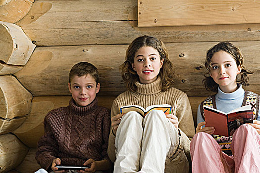 三个,年轻,兄弟姐妹,坐,并排,读,玩,电子游戏