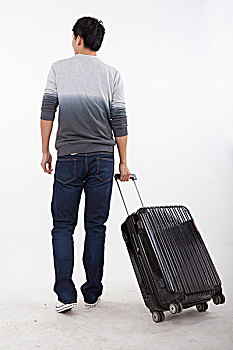 一个青年男子拉着手提箱