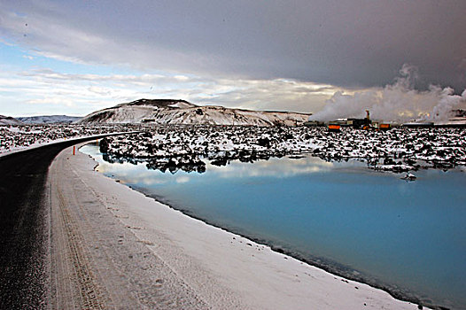 iceland,blue,lagoon,road,along,color,lake,with,snowy,lava,rock,in,the,background