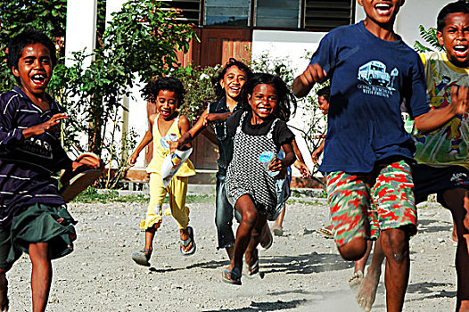 three,3,timorese,girl,in,a,refugee,camp,with,fingers,up,smiling