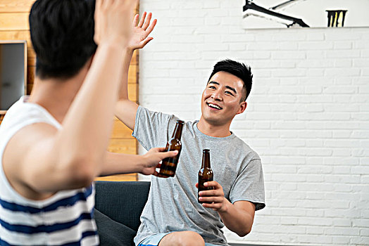 年轻男子坐在沙发喝啤酒