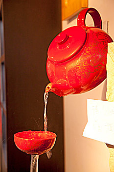 红色的茶壶在给红色的茶碗力倒茶