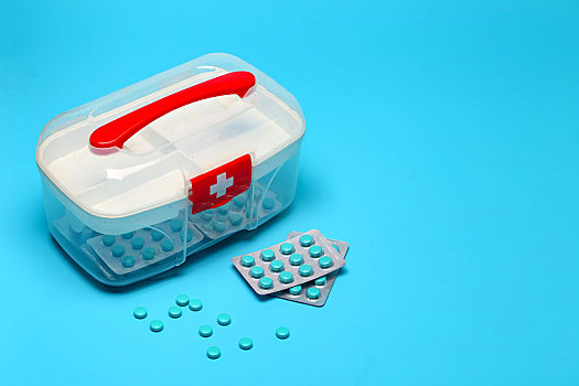 急救药箱和药片放在蓝色背景上