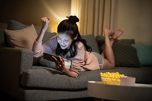 年轻女士在家玩手机游戏