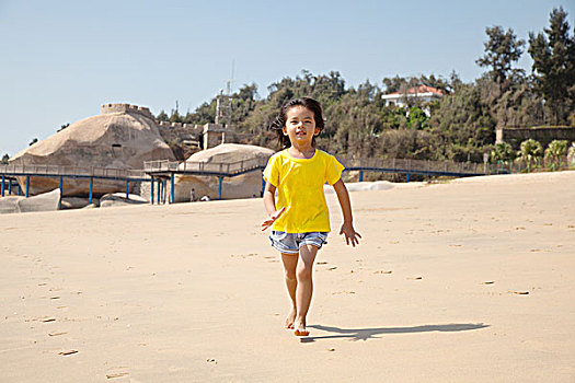 小女孩赤脚在沙滩奔跑