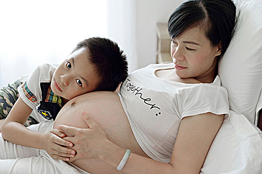 男孩贴在妈妈的肚子上听胎动