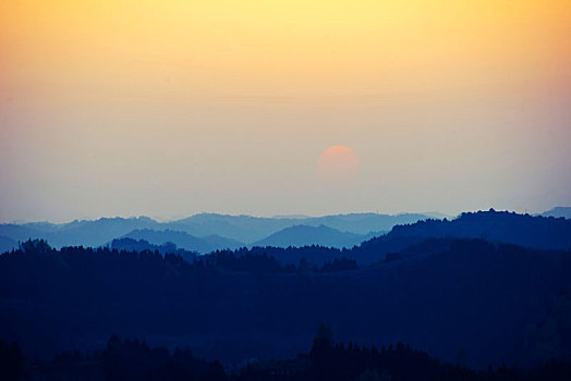 群山重叠落日在天空隐隐可见