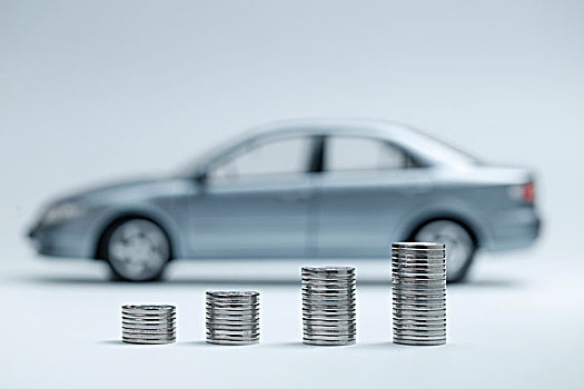 硬币堆放在汽车模型前,汽车贷款交易租赁销售概念