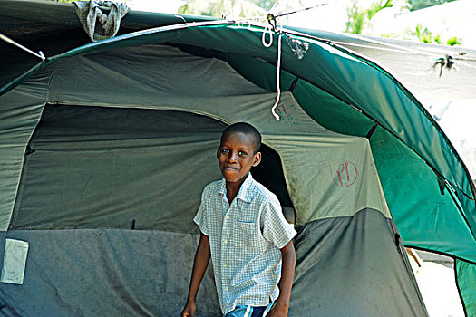 haiti,port,au,prince,young,boy,smiling,in,front,of,tent,refugee,camp