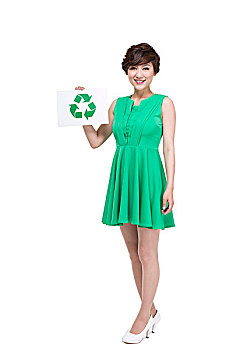 穿绿色裙子的年轻女人拿着环保标志