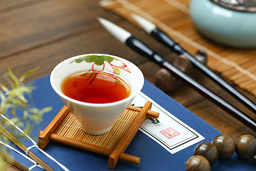 红茶,毛笔和线装书放在桌子上