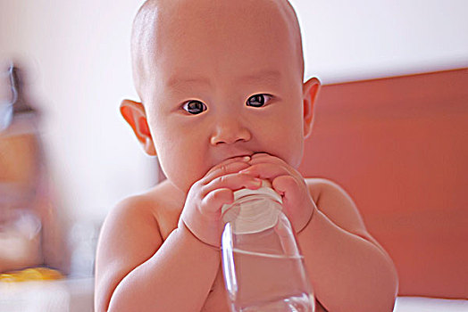 抱着奶瓶叼着奶嘴玩的婴儿