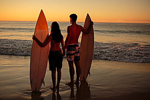 情侣,牵手,拿着,冲浪板,海滩,看,日落