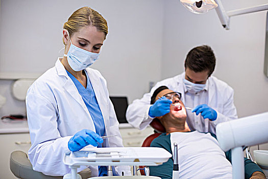 牙医,拿着,牙科工具,同事,检查,病人,背景,诊所