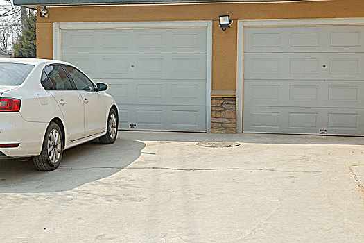 一辆白色轿车停在车库外awhitecarparkingoutofgarage