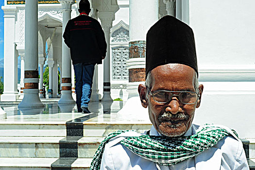 indonesia,sumatra,banda,aceh,old,man,with,traditional,hat,at,entrance,of,baiturrahman,grand,mosque,mesjid,raya