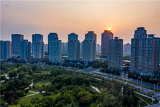 航拍河南省郑州市郑东新区cbd城市环形建筑群,夕阳下的红白花公园及商务内环商务外环高层建筑群