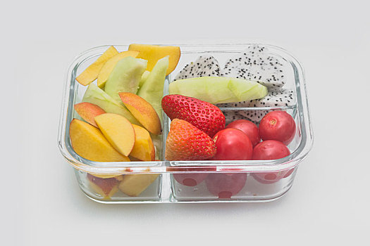 切好的各种水果组合由玻璃容器盛放,放在白色背景上