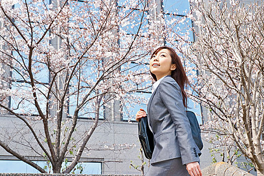 站在樱花树下的年轻女性