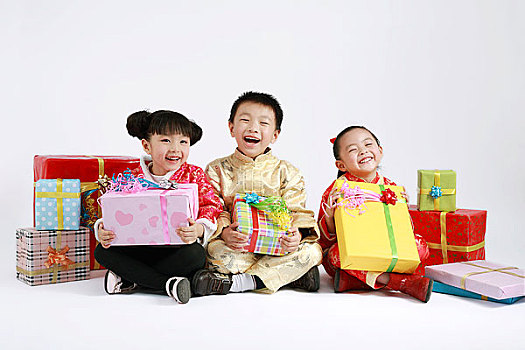 坐在一堆礼品盒中间的三个小孩