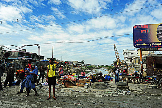 haiti,port,au,prince,presidential,campaign,advertisement,in,front,of,dried,and,polluted,river