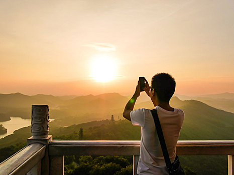 游客正在惠州高榜山挂榜阁用手机拍摄夕阳场景