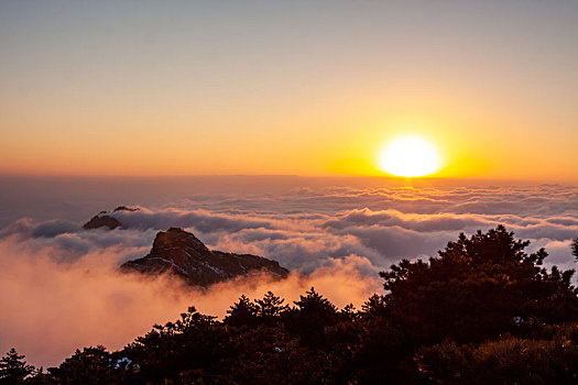中国安徽黄山风景区,冬日雪后放晴,夕阳映照山崖云雾飘渺宛若仙境