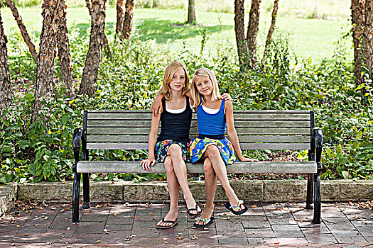 两个女孩,双腿交叉,长椅