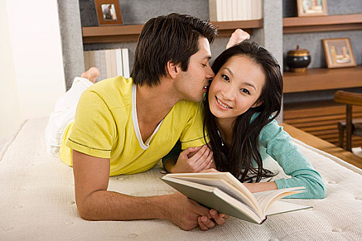 一对年轻的夫妻趴在床上看书