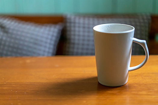 木质的桌面上有个白色的陶瓷杯
