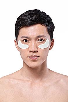 白色背景下面容清爽贴着眼膜的亚洲男青年