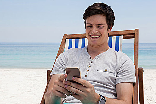 男人,坐,太阳椅,打手机,海滩,微笑