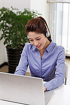 商务女士头戴耳机使用笔记本电脑