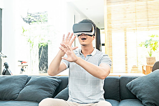 年輕男子在沙發(fā)上使用VR眼鏡