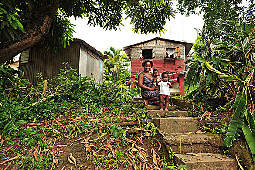 dominica,carib,territory,mother,with,son,waving,in,front,of,house