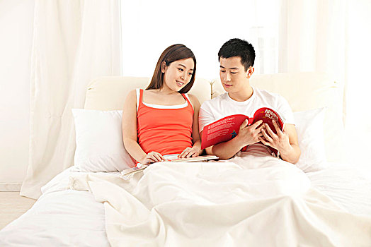 年轻夫妻躺在床上看书