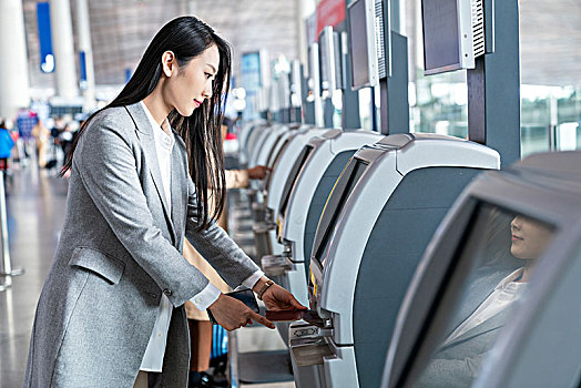 商务女子在机场使用自动售票机