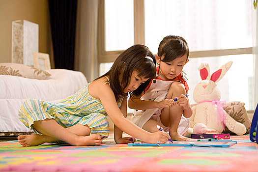 两个小女孩坐在地板上画画